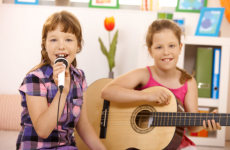 Young girl singing while her sister is playing the guitar