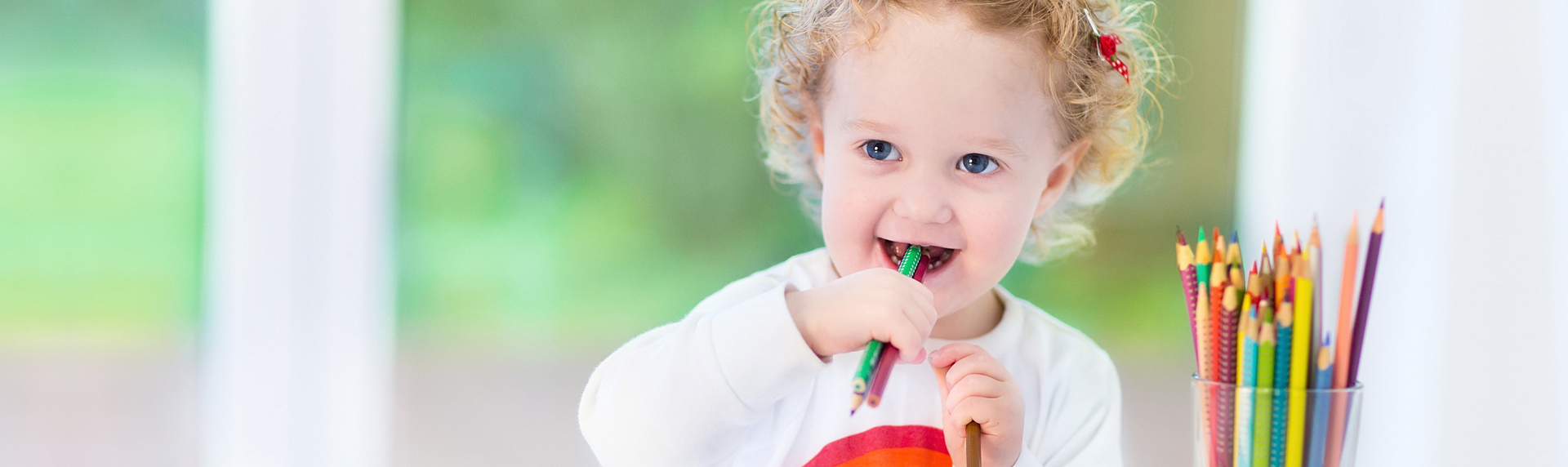 Cute baby biting colorful pencils
